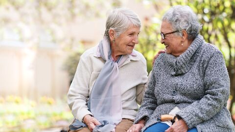 Zwei Frauen höheren Alters unterhalten sich sitzend 