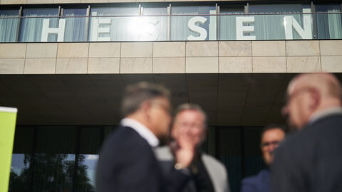 Momentaufnahme vom Hessenfest 2023 mit den HESSEN-Buchstaben im Hintergrund und Menschen im Gespräch im Vordergrund