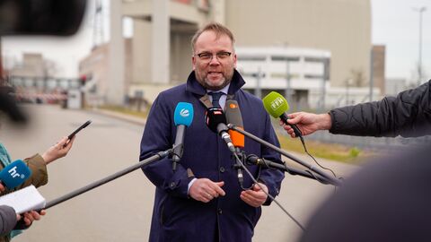 Wissenschaftsminister Gremmels steht in einer Interviewsituation vor Mikrofonen und spricht.