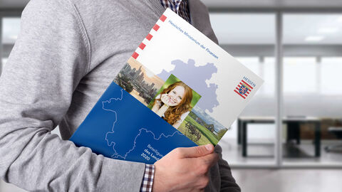 Ein Mann trägt den Beteiligungsbericht 2020 des Landes Hessen.