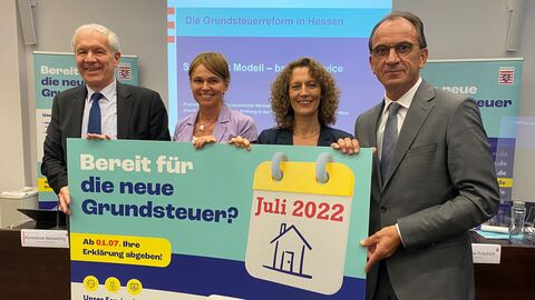 Zu sehen sind von links nach rechts Oberfinanzpräsident Jürgen Roßberg, die Finanzpräsidentinnen Dr. Susanne Friedrich und Konstanze Bepperling sowie Hessens Finanzminister Michael Boddenberg, die ein Plakat zur neuen Grundsteuer präsentieren.
